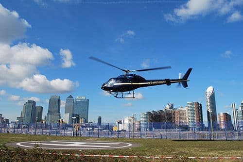 Twin Squirrel helicopter landing at a helipad with Canary Wharf behind